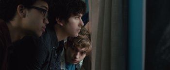 Movie still from “Paper Towns” (2015), directed by Jake Schreier – Two young men looking out a window at a curtain; Close Up shot, Low angle