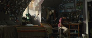 Movie still from “Paper Towns” (2015), directed by Jake Schreier – A man sitting at a table in a room; Wide shot, High angle