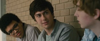 Movie still from “Paper Towns” (2015), directed by Jake Schreier – A young man sitting in front of a brick wall; Close Up shot, Over the shoulder angle