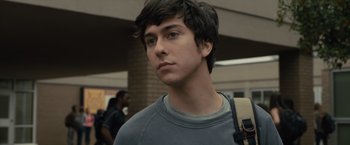 Movie still from “Paper Towns” (2015), directed by Jake Schreier – A young man with long black hair wearing a gray shirt; Close Up shot, Over the shoulder angle