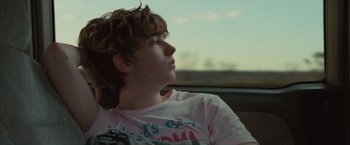 Movie still from “Paper Towns” (2015), directed by Jake Schreier – A young man sitting in the back seat of a car looking out the window; Close Up shot, Over the shoulder angle
