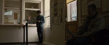 Movie still from “Paper Towns” (2015), directed by Jake Schreier – A man standing in front of a window looking at his cell phone; Wide shot, Low angle