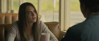 Movie still from “Paper Towns” (2015), directed by Jake Schreier – A beautiful young lady sitting at a table with a drink; Close Up shot, Over the shoulder angle