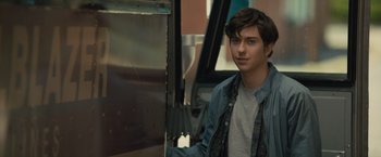 Movie still from “Paper Towns” (2015), directed by Jake Schreier – A young man standing next to an escalator; Close Up shot, Over the shoulder angle