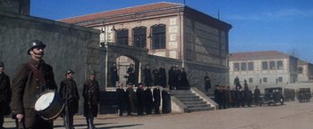 Movie still from “Papillon” (1973), directed by Franklin J. Schaffner – A group of men standing in front of a building; Extreme Wide shot, Low angle