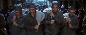 Movie still from “Papillon” (1973), directed by Franklin J. Schaffner – A group of men walking down a street holding ropes; Medium shot, Low angle