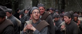 Movie still from “Papillon” (1973), directed by Franklin J. Schaffner – A group of men in old - fashioned clothing walking down a street; Medium shot, Low angle