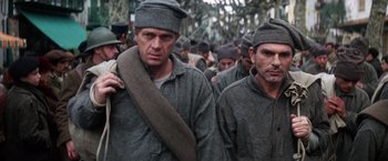 Movie still from “Papillon” (1973), directed by Franklin J. Schaffner – A group of men in grey jackets and hats; Medium shot, High angle