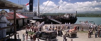 Movie still from “Papillon” (1973), directed by Franklin J. Schaffner – A crowd of people standing on a dock next to a boat; Extreme Wide shot, High angle