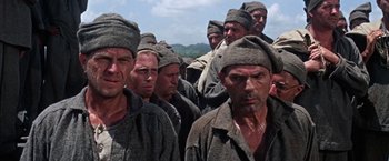 Movie still from “Papillon” (1973), directed by Franklin J. Schaffner – A large group of men in military uniforms standing in a line; Close Up shot, Low angle