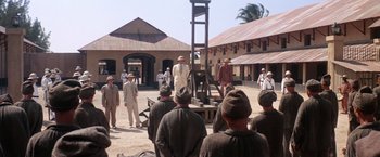 Movie still from “Papillon” (1973), directed by Franklin J. Schaffner – A group of men standing around a guillotine; Extreme Wide shot, High angle