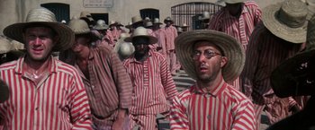Movie still from “Papillon” (1973), directed by Franklin J. Schaffner – A group of men in striped shirts and straw hats; Wide shot, High angle