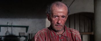 Movie still from “Papillon” (1973), directed by Franklin J. Schaffner – An older man with a beard and a striped shirt; Close Up shot, High angle