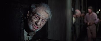 Movie still from “Papillon” (1973), directed by Franklin J. Schaffner – An old man with white hair and blue eyes looking at the camera; Close Up shot, Low angle