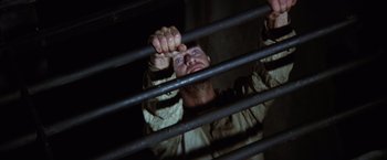 Movie still from “Papillon” (1973), directed by Franklin J. Schaffner – A man holding on to a metal fence; Close Up shot, Overhead angle