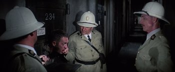 Movie still from “Papillon” (1973), directed by Franklin J. Schaffner – A man that is wearing a uniform; Medium shot, Over the shoulder angle