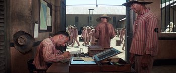 Movie still from “Papillon” (1973), directed by Franklin J. Schaffner – A group of men in robes and hats walking in a courtyard; Wide shot, High angle