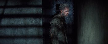 Movie still from “Papillon” (1973), directed by Franklin J. Schaffner – A man in a dark room with blood all over his face; Medium shot, Low angle