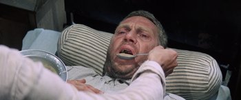 Movie still from “Papillon” (1973), directed by Franklin J. Schaffner – A person with a spoon in his mouth; Close Up shot, Overhead angle