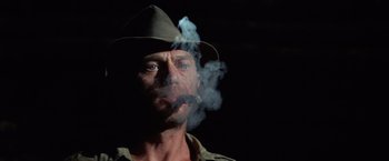 Movie still from “Papillon” (1973), directed by Franklin J. Schaffner – A person with a hat smoking a cigar; Close Up shot, Low angle