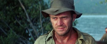 Movie still from “Papillon” (1973), directed by Franklin J. Schaffner – A person wearing a hat with trees in the background; Close Up shot, Over the shoulder angle