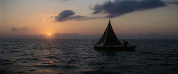 Movie still from “Papillon” (1973), directed by Franklin J. Schaffner – A sailboat in the middle of the ocean at sunset; Extreme Wide shot, Low angle