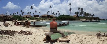 Movie still from “Papillon” (1973), directed by Franklin J. Schaffner – A man sitting on a log on the beach; Wide shot, High angle