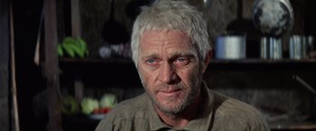 Movie still from “Papillon” (1973), directed by Franklin J. Schaffner – An older man with white hair and blue eyes stares at the camera; Close Up shot, Low angle