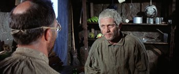 Movie still from “Papillon” (1973), directed by Franklin J. Schaffner – An older man with white hair is talking to another man; Close Up shot, Over the shoulder angle