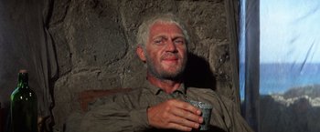 Movie still from “Papillon” (1973), directed by Franklin J. Schaffner – An old man with white hair is holding a cup; Close Up shot, High angle
