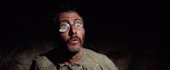 Movie still from “Papillon” (1973), directed by Franklin J. Schaffner – A man wearing glasses and a sweater looking at the camera; Close Up shot, Low angle