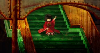 Movie still from “Paprika” (2006), directed by Satoshi Kon – A doll sitting on top of a set of green stairs; Wide shot, Overhead angle