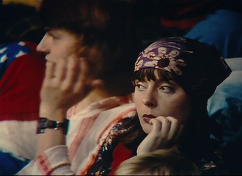 Movie still from “Parade” (1974), directed by Jacques Tati – A woman sitting next to a man with her hand under her chin; Close Up shot, High angle