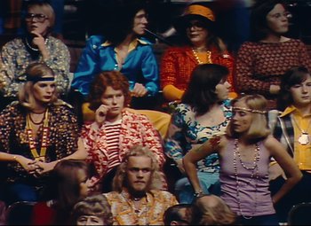 Movie still from “Parade” (1974), directed by Jacques Tati – A group of people sitting in a room; Medium shot, High angle