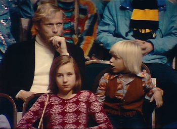 Movie still from “Parade” (1974), directed by Jacques Tati – A man and two young girls sitting next to each other; Medium shot, High angle