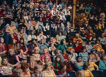 Movie still from “Parade” (1974), directed by Jacques Tati – A large crowd of people sitting in a stadium; Extreme Wide shot, High angle