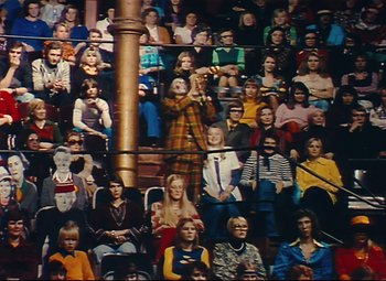 Movie still from “Parade” (1974), directed by Jacques Tati – A large group of people sitting in a room; Extreme Wide shot, High angle