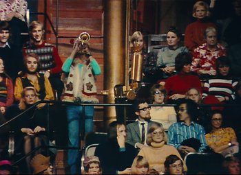 Movie still from “Parade” (1974), directed by Jacques Tati – A group of people sitting and standing in front of a microphone; Extreme Wide shot, High angle