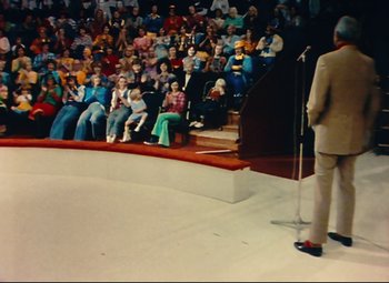 Movie still from “Parade” (1974), directed by Jacques Tati – A man is speaking in front of an audience; Wide shot, High angle