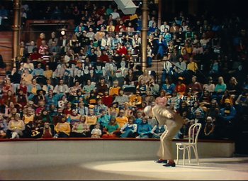 Movie still from “Parade” (1974), directed by Jacques Tati – A man standing in front of a wall of people; Extreme Wide shot, High angle