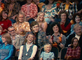 Movie still from “Parade” (1974), directed by Jacques Tati – A group of people sitting and standing in a room; Wide shot, High angle