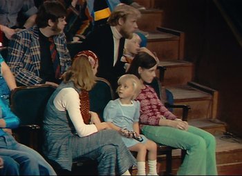 Movie still from “Parade” (1974), directed by Jacques Tati – A group of people sitting in a row of seats; Wide shot, High angle