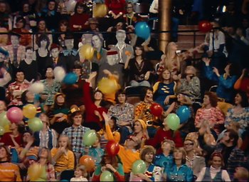 Movie still from “Parade” (1974), directed by Jacques Tati – A crowd of people sitting and standing in a stadium; Extreme Wide shot, High angle