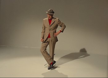 Movie still from “Parade” (1974), directed by Jacques Tati – A man in a suit and hat posing for a picture; Wide shot, Low angle