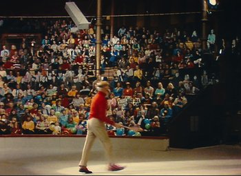 Movie still from “Parade” (1974), directed by Jacques Tati – A man in a red shirt is playing a game of baseball; Extreme Wide shot, High angle