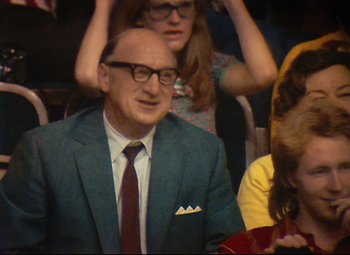 Movie still from “Parade” (1974), directed by Jacques Tati – An older man wearing a suit and tie; Medium shot, Over the shoulder angle