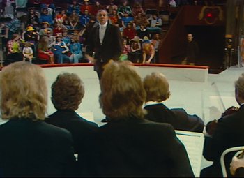 Movie still from “Parade” (1974), directed by Jacques Tati – A group of people sitting in front of an audience on a stage; Extreme Wide shot, High angle