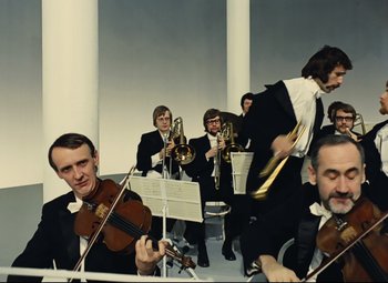 Movie still from “Parade” (1974), directed by Jacques Tati – A group of men in suits and ties playing musical instruments; Wide shot, Low angle