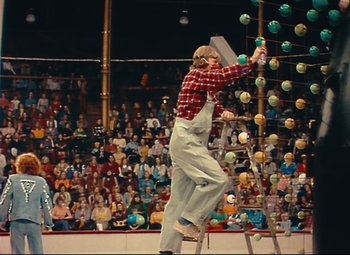 Movie still from “Parade” (1974), directed by Jacques Tati – A man standing on top of a step ladder in front of an audience; Wide shot, Low angle