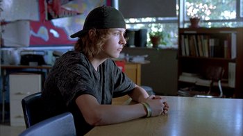 Movie still from “Paranoid Park” (2007), directed by Gus Van Sant – A man sitting at a table with his arms crossed; Medium shot, Over the shoulder angle